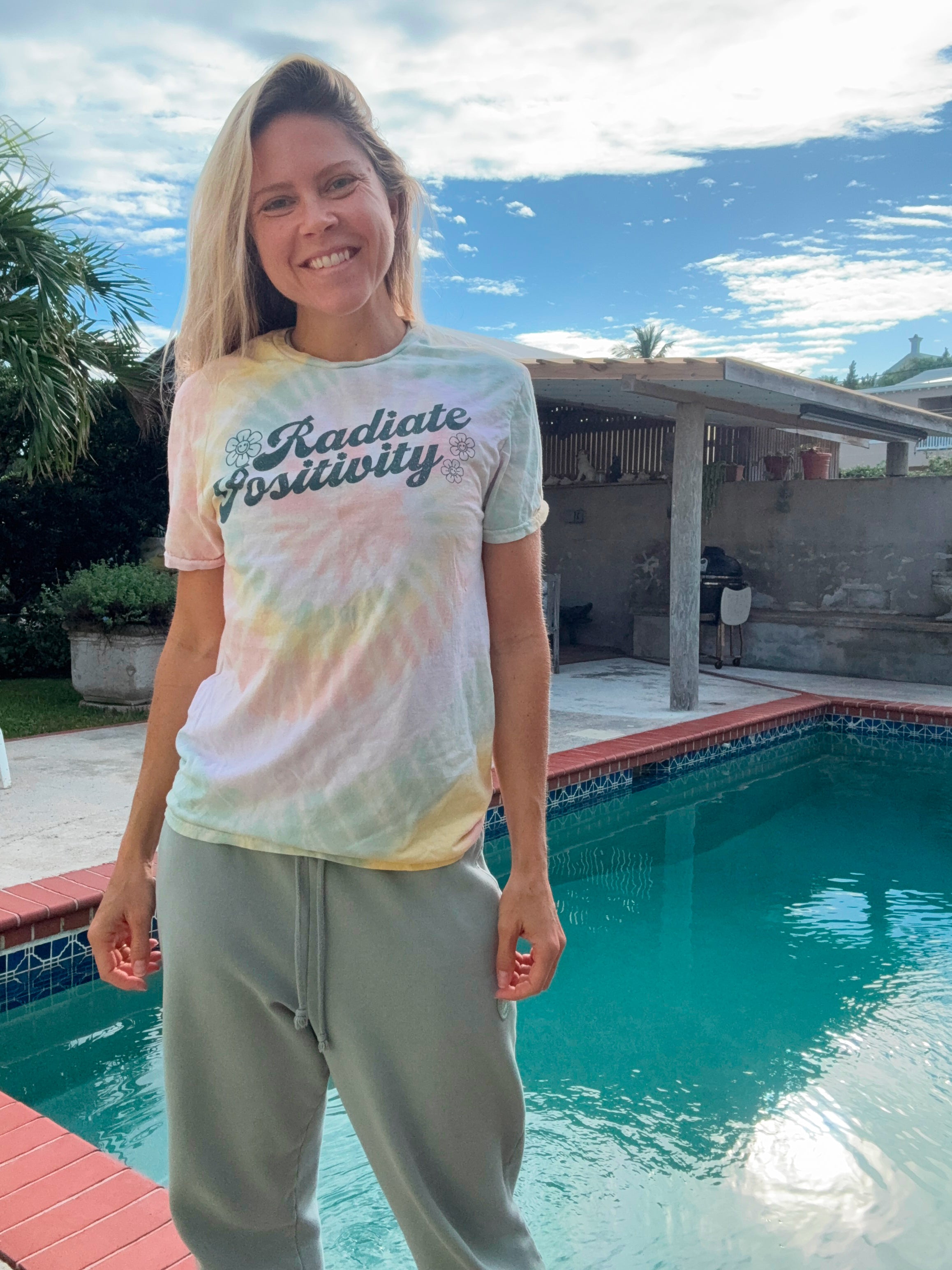 Amy wearing a Radiate Positivity tie dye shirt by the pool